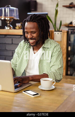 Young man using laptop in cafeteria Stock Photo