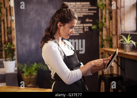 Waitress using digital tablet in cafeteria Stock Photo