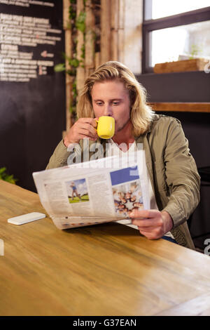 Man drinking a coffee while is reading a newspaper Stock Photo