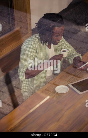 Man drinking coffee and using smartphone Stock Photo