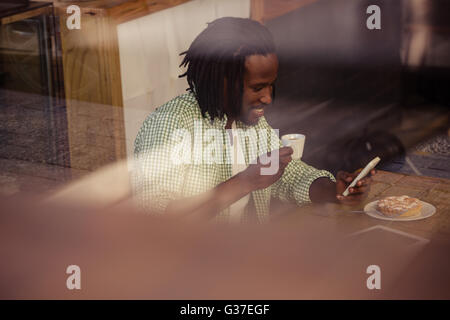 Man drinking coffee and using smartphone Stock Photo