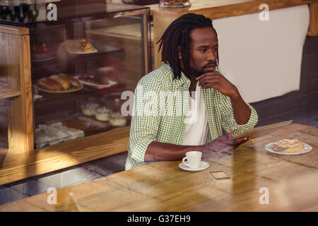 Thoughtful man using tablet Stock Photo