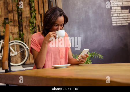 Woman drinking coffee and using smartphone Stock Photo