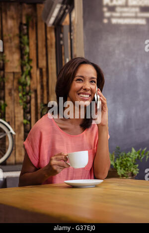 Woman drinking coffee and using smartphone Stock Photo