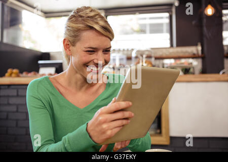 Woman using a tablet sitting and smiling Stock Photo