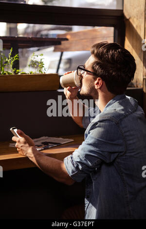 Man drinking coffee and using smartphone Stock Photo