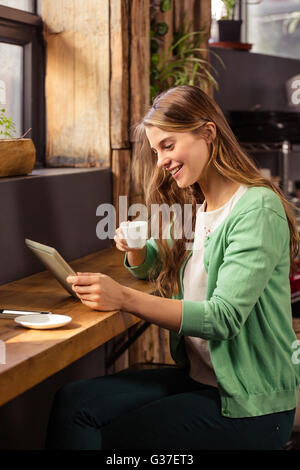 Smiling woman drinking coffee and using tablet Stock Photo