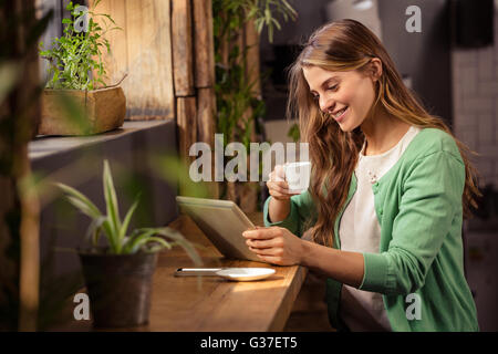 Smiling woman drinking coffee and using tablet Stock Photo