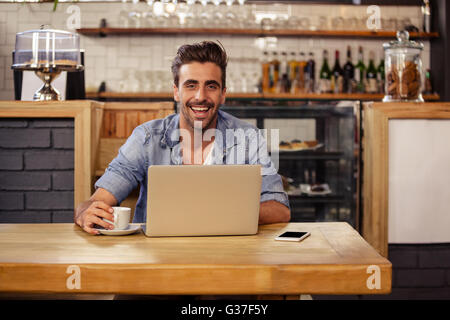Hipster man smiling at camera while using laptop Stock Photo