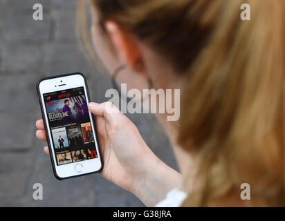 A young woman uses an app by streaming provider Netflix on her smartphone, photographed at the premiere of the Netflix series 'Orange is the new Black - 4th series' in Berlin, 7 June 2016. Netflix is the worldwide leading subscription service for mobile streaming of movies and series. Photo: Jens Kalaene/dpa Stock Photo