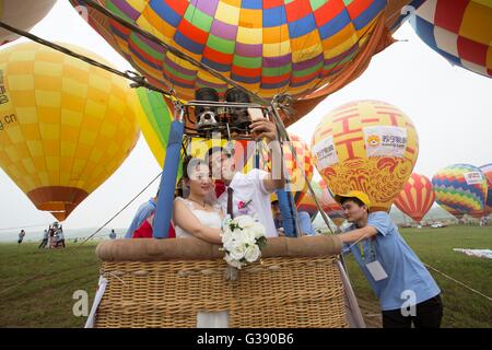 Nanjing, China's Jiangsu Province. 10th June, 2016. A newlywed takes a hot-air balloon during a group wedding ceremony in Nanjing, capital of east China's Jiangsu Province, June 10, 2016. A total of 50 newlyweds took part in the hot-air balloon wedding. Credit:  Yan Minhang/Xinhua/Alamy Live News Stock Photo