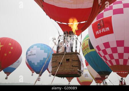 Nanjing, China's Jiangsu Province. 10th June, 2016. A newlywed takes a hot-air balloon during a group wedding ceremony in Nanjing, capital of east China's Jiangsu Province, June 10, 2016. A total of 50 newlyweds took part in the hot-air balloon wedding. Credit:  Yan Minhang/Xinhua/Alamy Live News Stock Photo