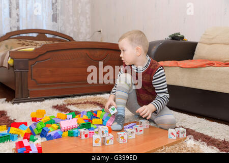 boy playing with blocks and train on the floor Stock Photo