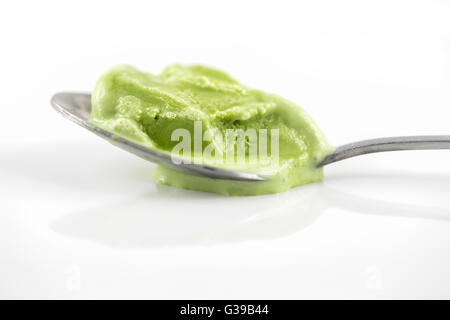 Close focus on green tea ice cream melting on teaspoon which putting on shining white surface. Stock Photo