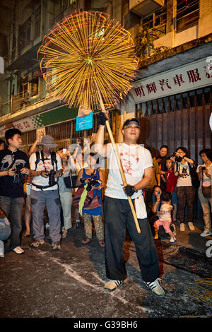 A carrier hoists aloft the quivering and fiery incense laden head of the now famous Fire Dragon Dance in Tai Hang, Hong Kong. Stock Photo