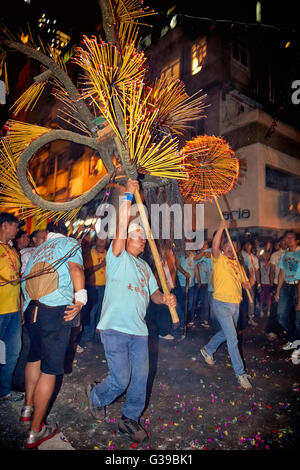 A carrier hoists aloft the quivering and fiery incense laden head of the now famous Fire Dragon Dance in Tai Hang, Hong Kong. Stock Photo