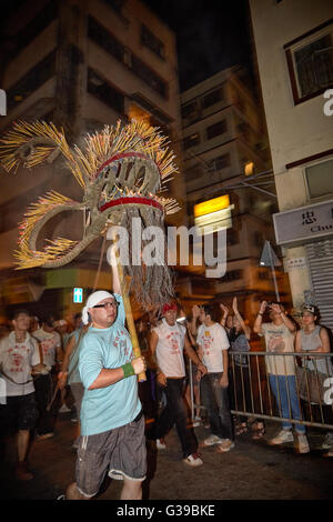 A carrier hoists aloft the quivering and fiery incense laden head of the now famous Fire Dragon Dance in Tai Hang, Hong Kong. Stock Photo