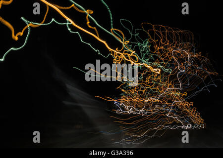 abstract curves traces of multi-colored trails of light on a dark background look like a spider web Stock Photo