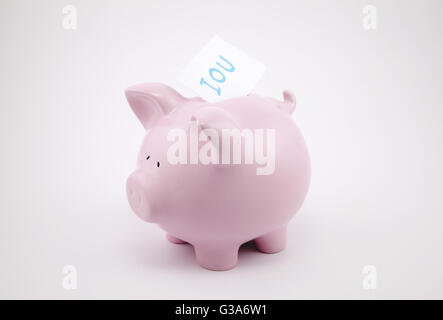 Pink piggy bank with IOU sticking out of its coin slot. Stock Photo