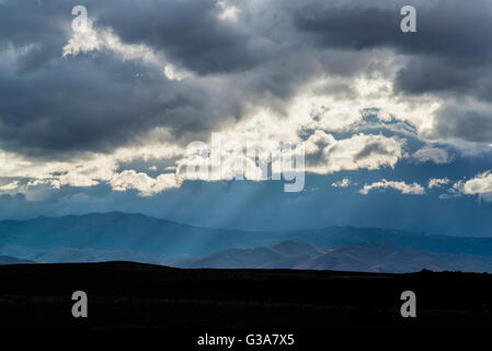 Sun rays breaking through clouds in front of the Owyhee Mountains in Southern Idaho. Stock Photo