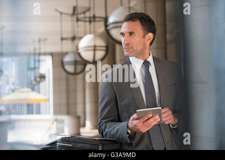 Corporate businessman with digital tablet looking away Stock Photo