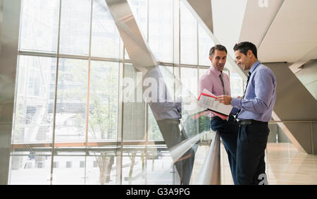 Corporate businessmen discussing paperwork in modern lobby Stock Photo