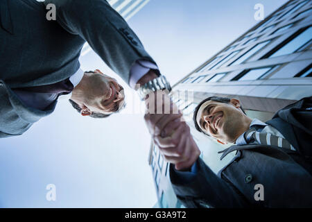 Corporate businessmen handshaking below building Stock Photo