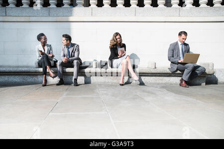 Corporate business people working on sunny bench outdoors Stock Photo