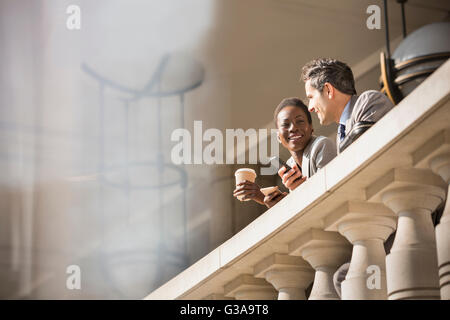 Corporate businessman and businesswoman drinking coffee at railing Stock Photo