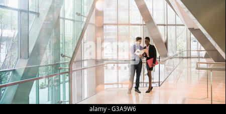 Corporate businessman and businesswoman discussing paperwork in modern lobby Stock Photo