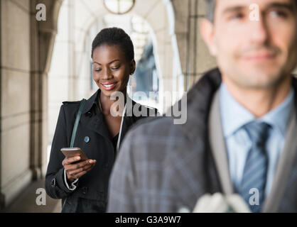 Corporate businesswoman texting with cell phone in cloister Stock Photo
