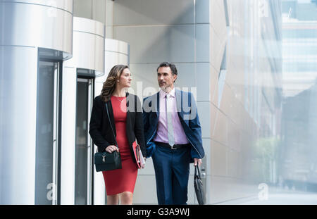 Corporate businessman and businesswoman walking and talking outside building Stock Photo