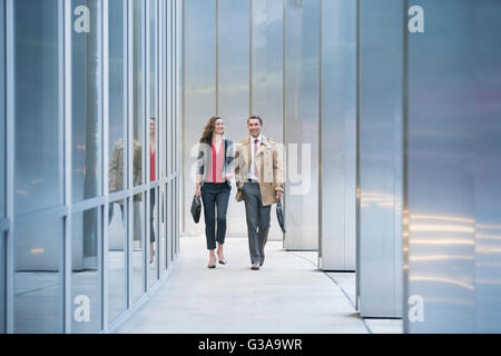 Corporate businessman and businesswoman walking along modern building Stock Photo
