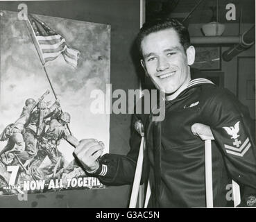 Navy Pharmacist's Mate Second Class John H. Bradley points to the 7th War Loan poster which bears the historic picture of the flag raising on Mount Suribachi, Iwo Jima. Bradley participated in the event while attached to a Marine unit in the battle. Stock Photo