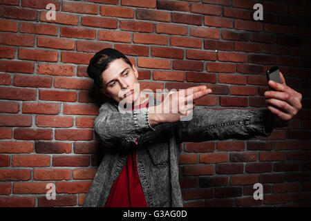 Young man in casual clothes make selfie on a background of red brick wall Stock Photo