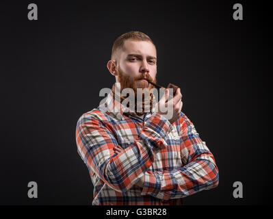 Elegant bearded man holding smoking pipe Stock Photo