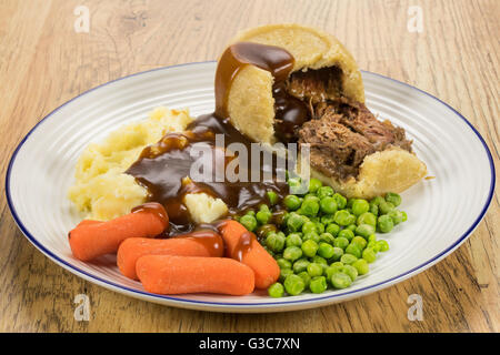 A steak and kidney suet pudding pie dinner with vegetables. Stock Photo