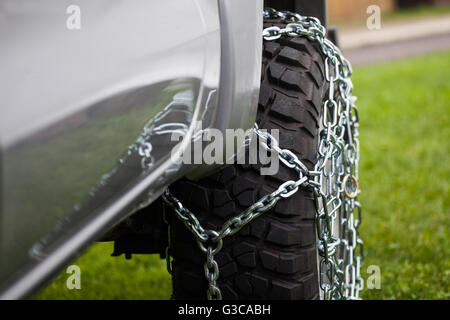 Close up shot of some chains wrapped around a car's tire. Stock Photo