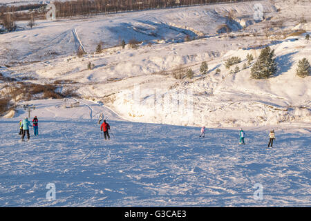 People skiing and snowboarding on the slopes of snow-covered hill Stock Photo