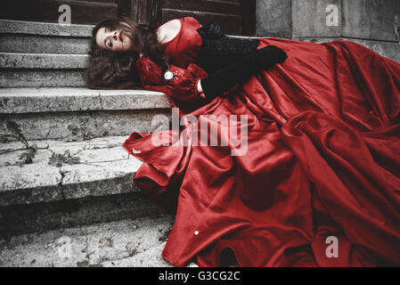 Lying and bleeding woman in a red Victorian dress