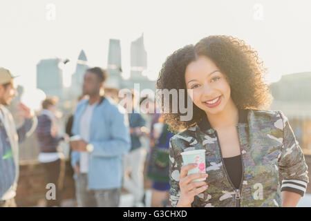 Portrait smiling young woman drinking cocktail at rooftop party Stock Photo