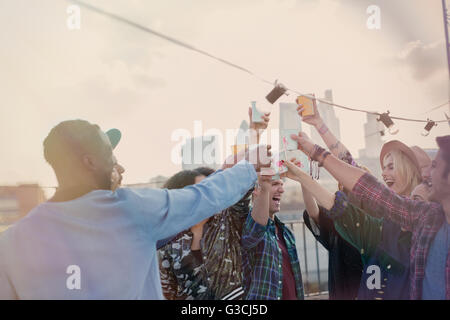Enthusiastic young adult friends toasting cocktails at rooftop party Stock Photo