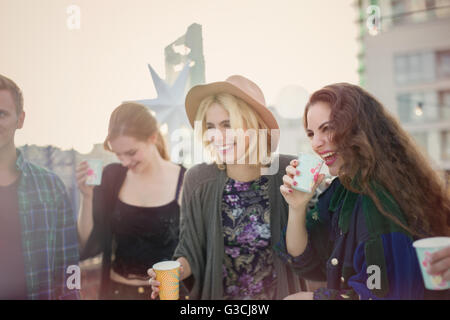 Smiling young women drinking and laughing at rooftop party Stock Photo