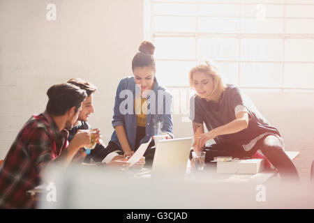 Creative young business people brainstorming at laptop in sunny office Stock Photo