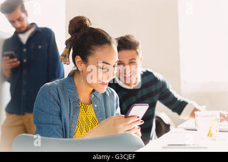 Smiling young business people texting with cell phone Stock Photo