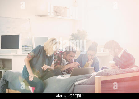 College students studying at laptop on bed in sunny dorm room Stock Photo