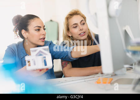 Female architects holding house model at computer in office Stock Photo