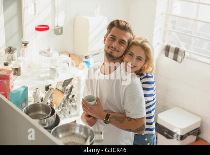 Portrait smiling young couple hugging in apartment kitchen Stock Photo