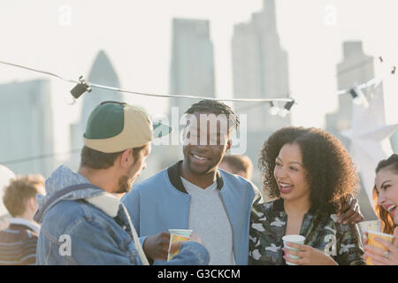 Young adult friends talking and drinking at rooftop party Stock Photo