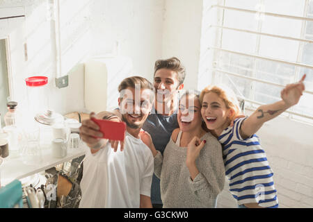 Enthusiastic young adult roommates taking selfie in kitchen